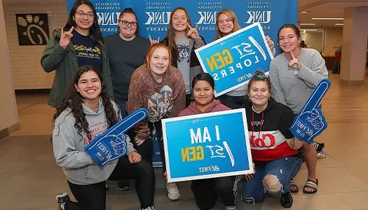 a group of students post with a sign that reads first gen